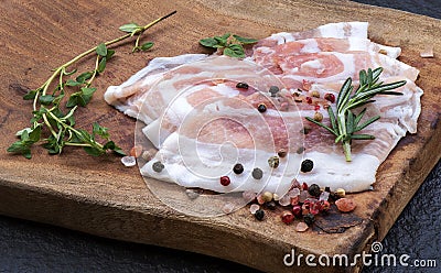 Sliced â€‹â€‹bacon with thyme rosemary and peppercorn on Chopping Wood Stock Photo